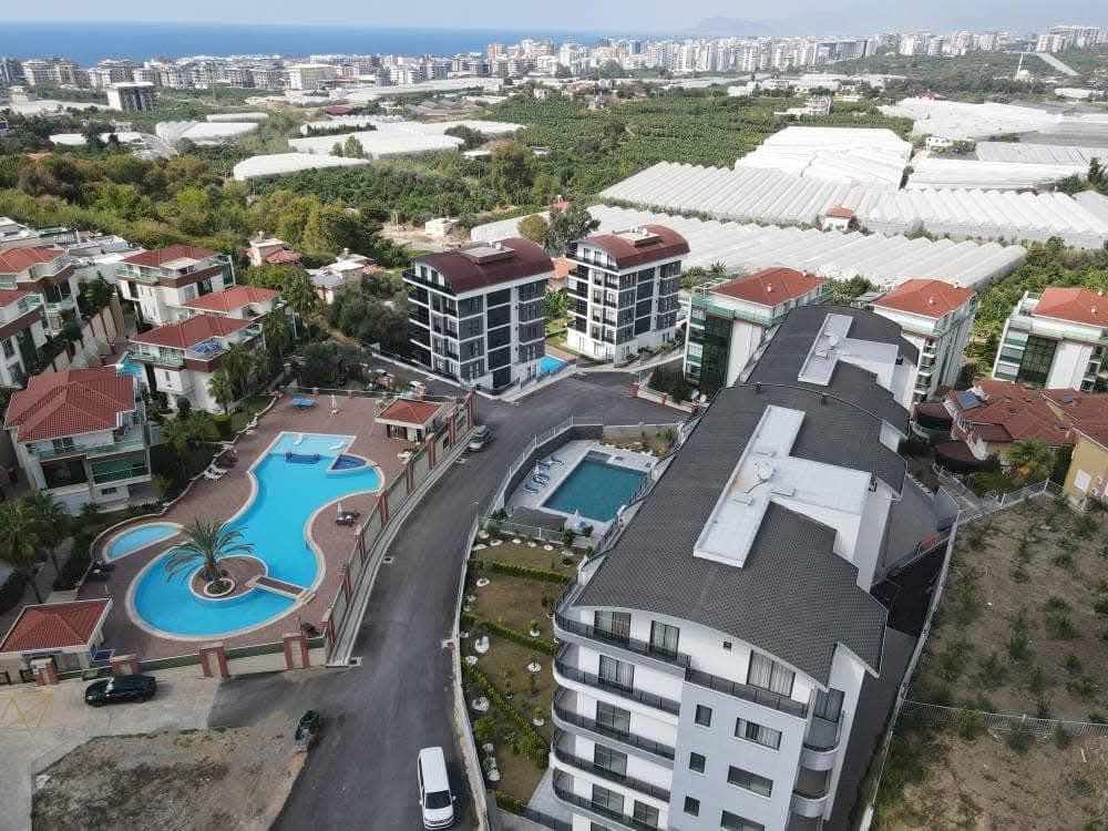Aerial view of pools and villas in Kargicak with the sea on the horizon where residences are for sale