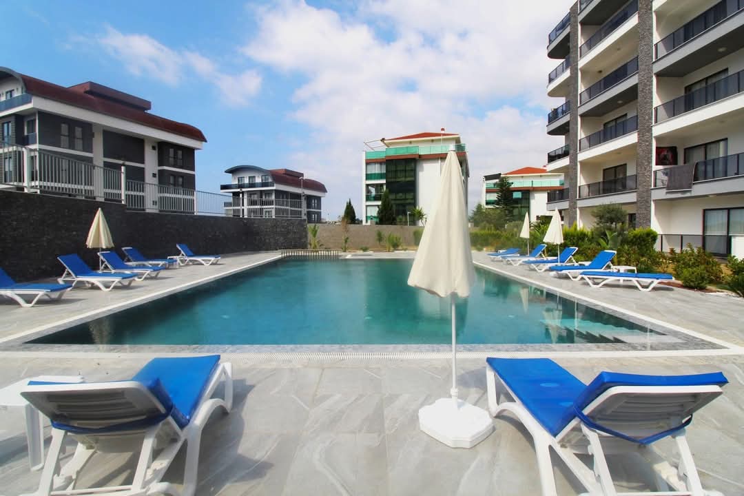 Rectangular pool with blue loungers on the grounds of a residence complex in Kargicak, Turkey