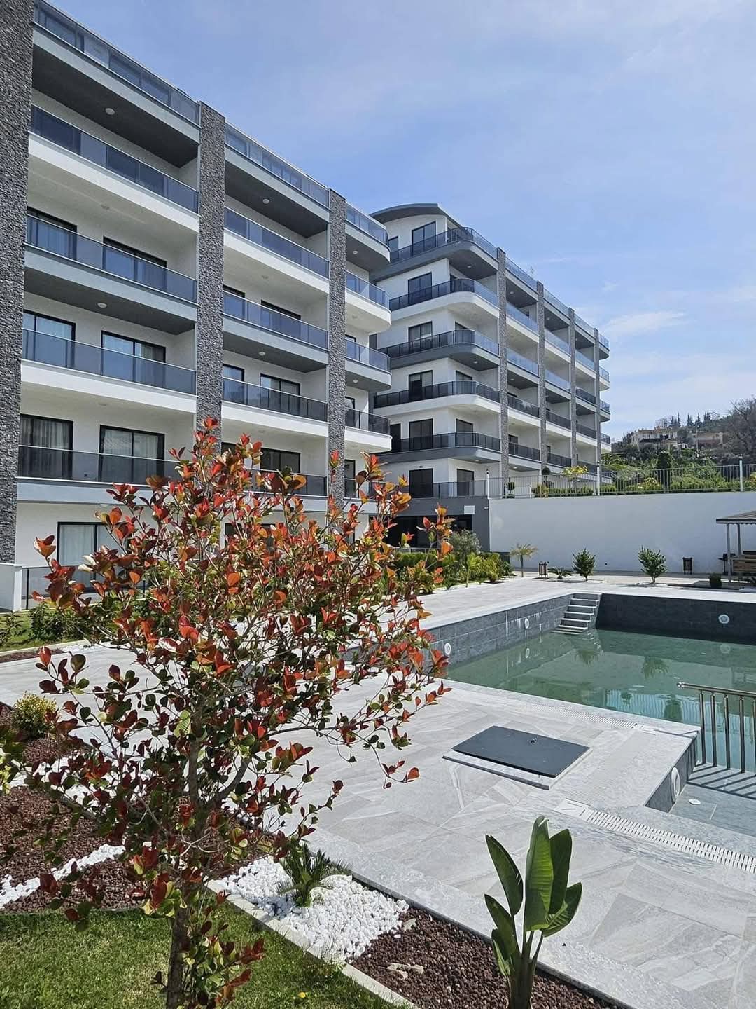 Küçük açık havuz ve merdiven penthouse dairelerin bulunduğu konut yapısının önünde yer alıyor