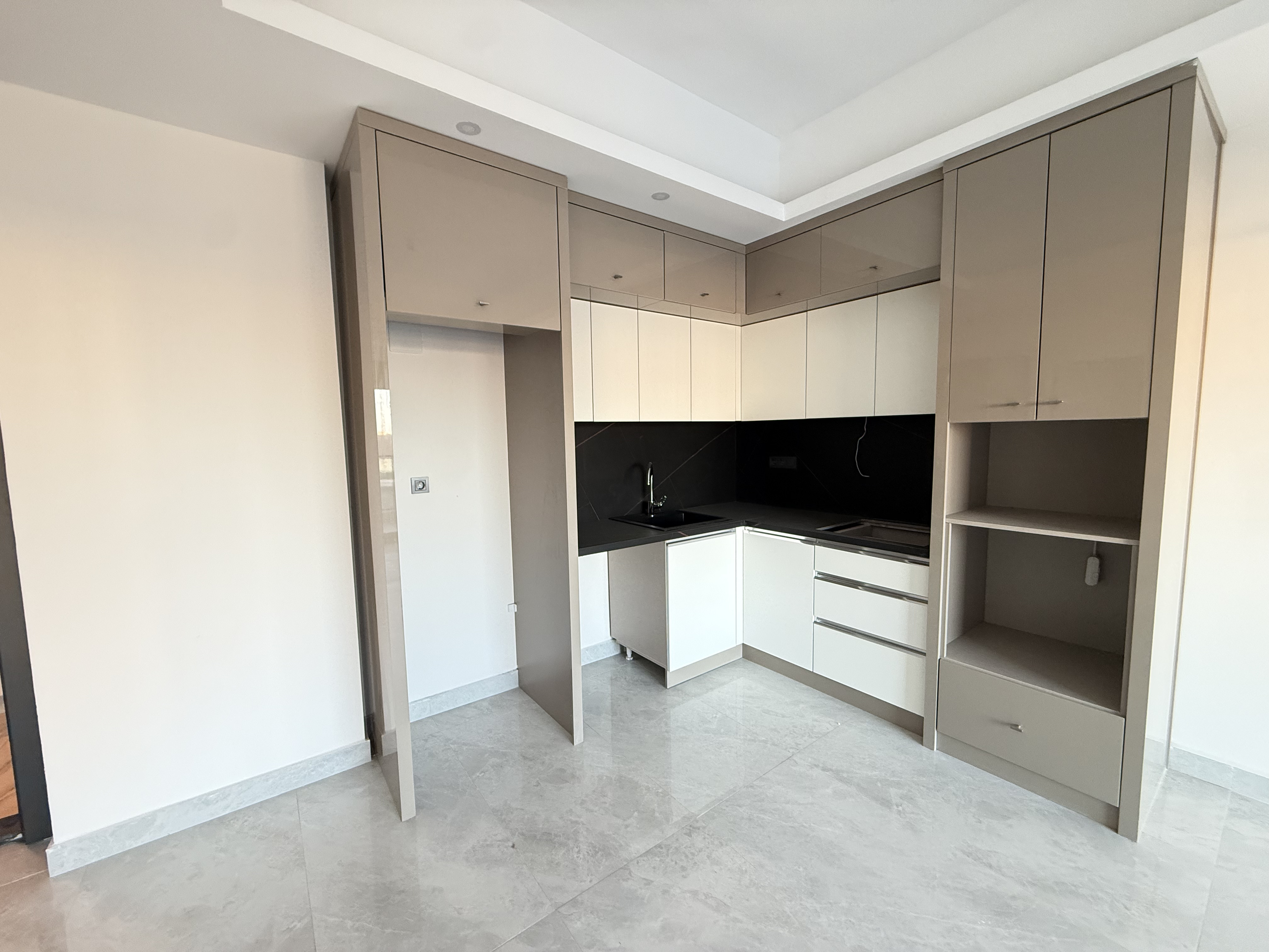 Kitchen with a corner fitted cabinet and black backsplash in an apartment in Mahmutlar
