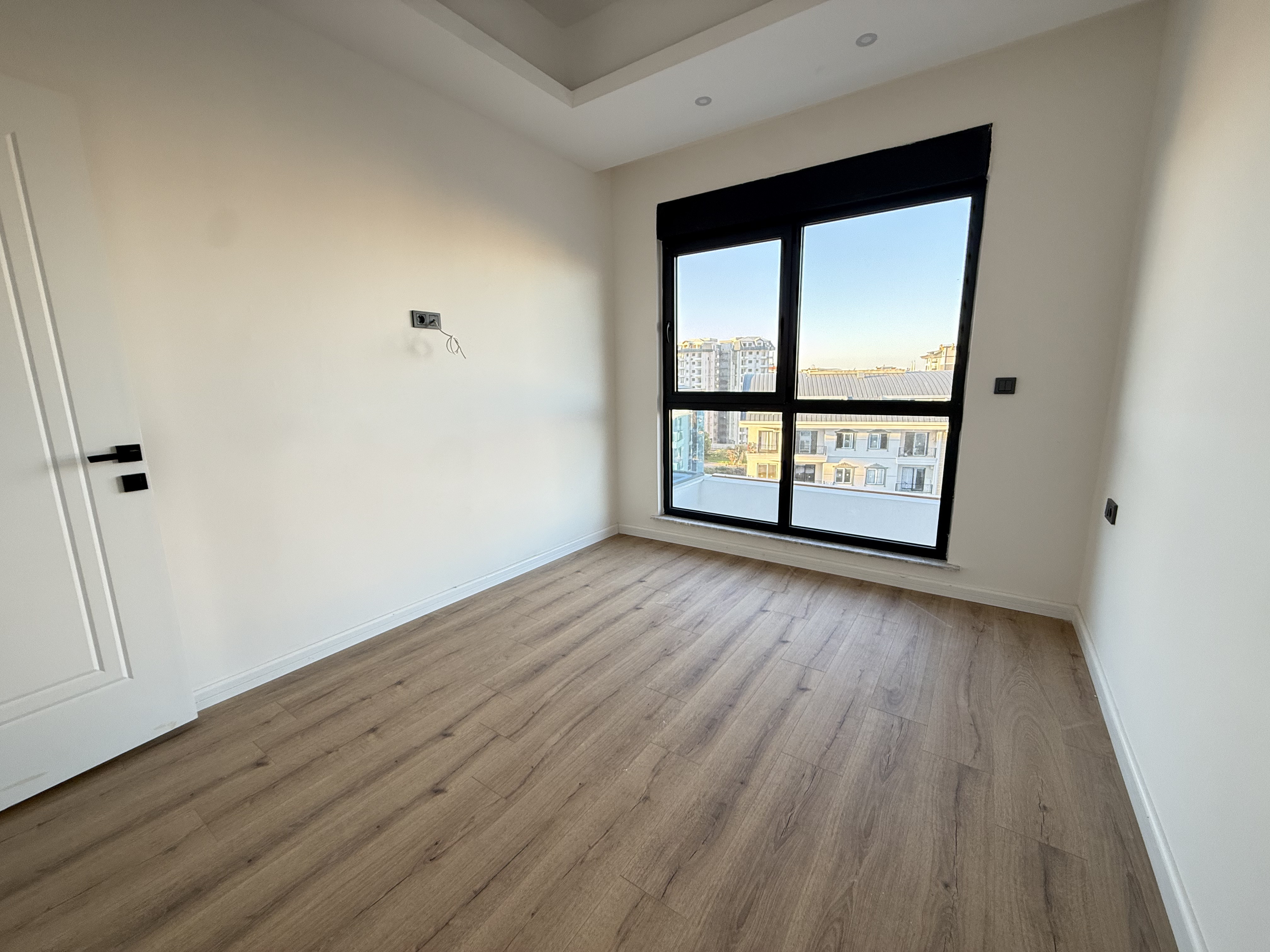 Bedroom with a wide window and white door in an apartment in Mahmutlar
