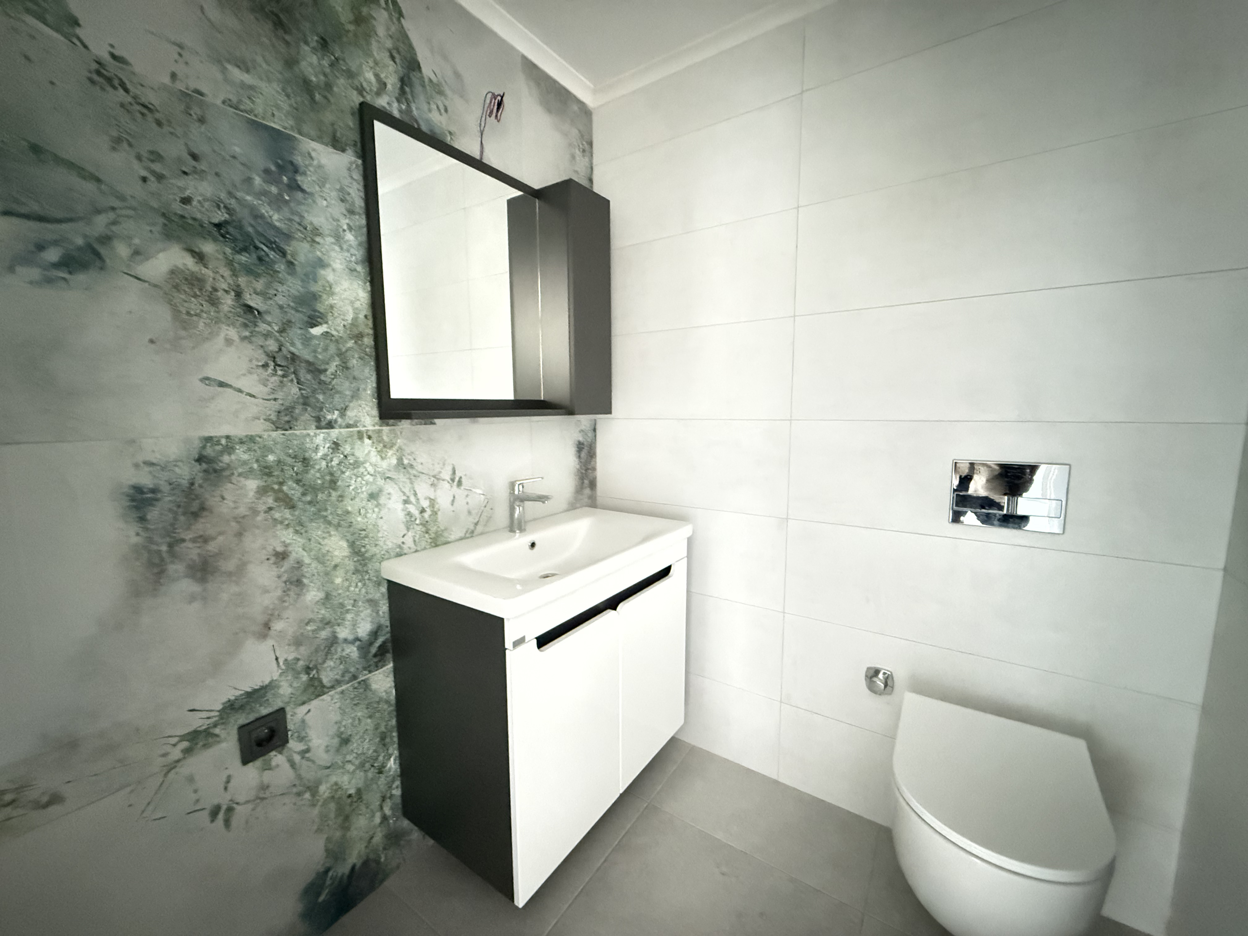 Bathroom with a wall-mounted vanity and decorative botanical tiles in Mahmutlar