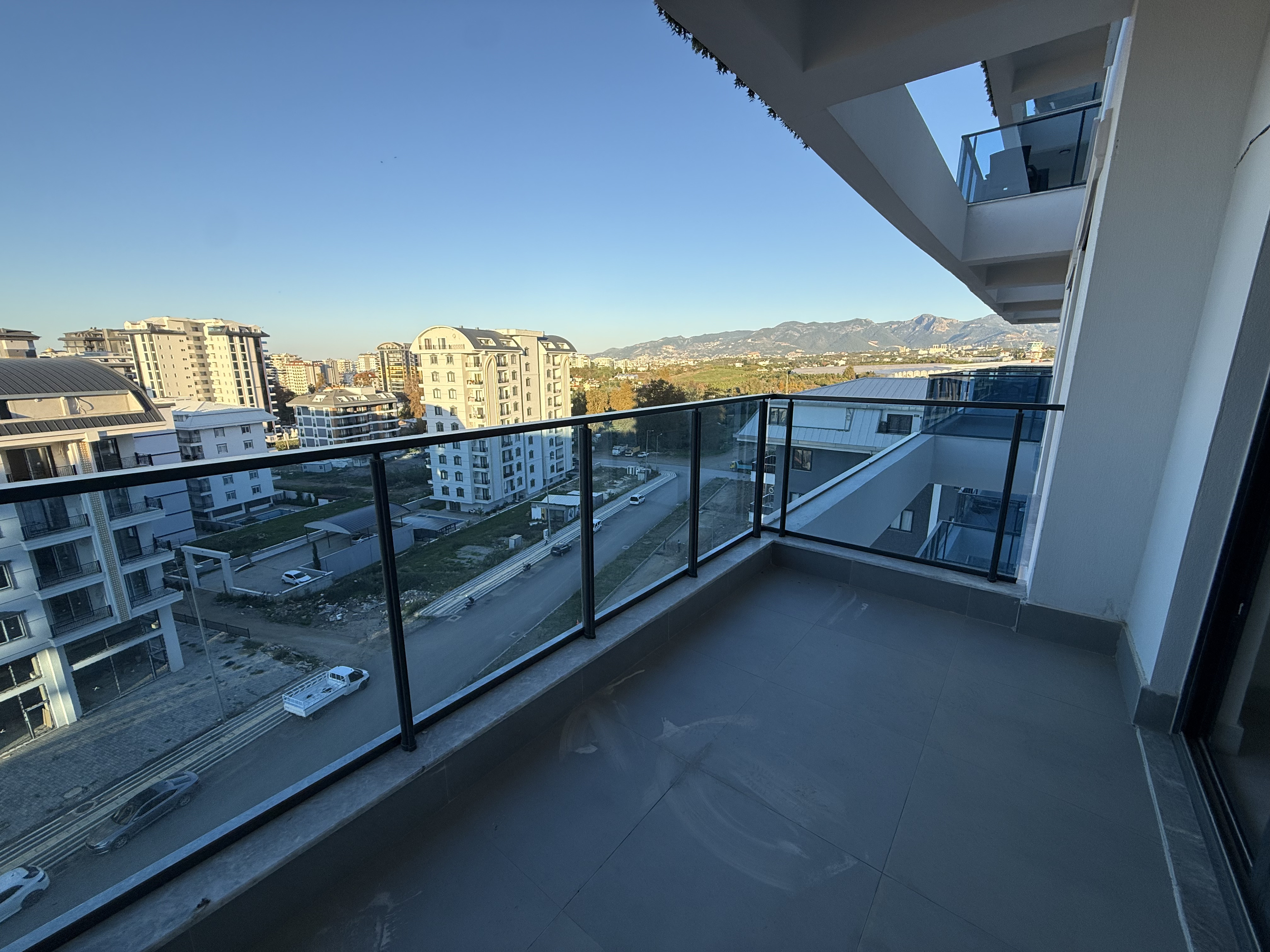 Corner balcony with a glass railing and mountain views in an apartment for sale