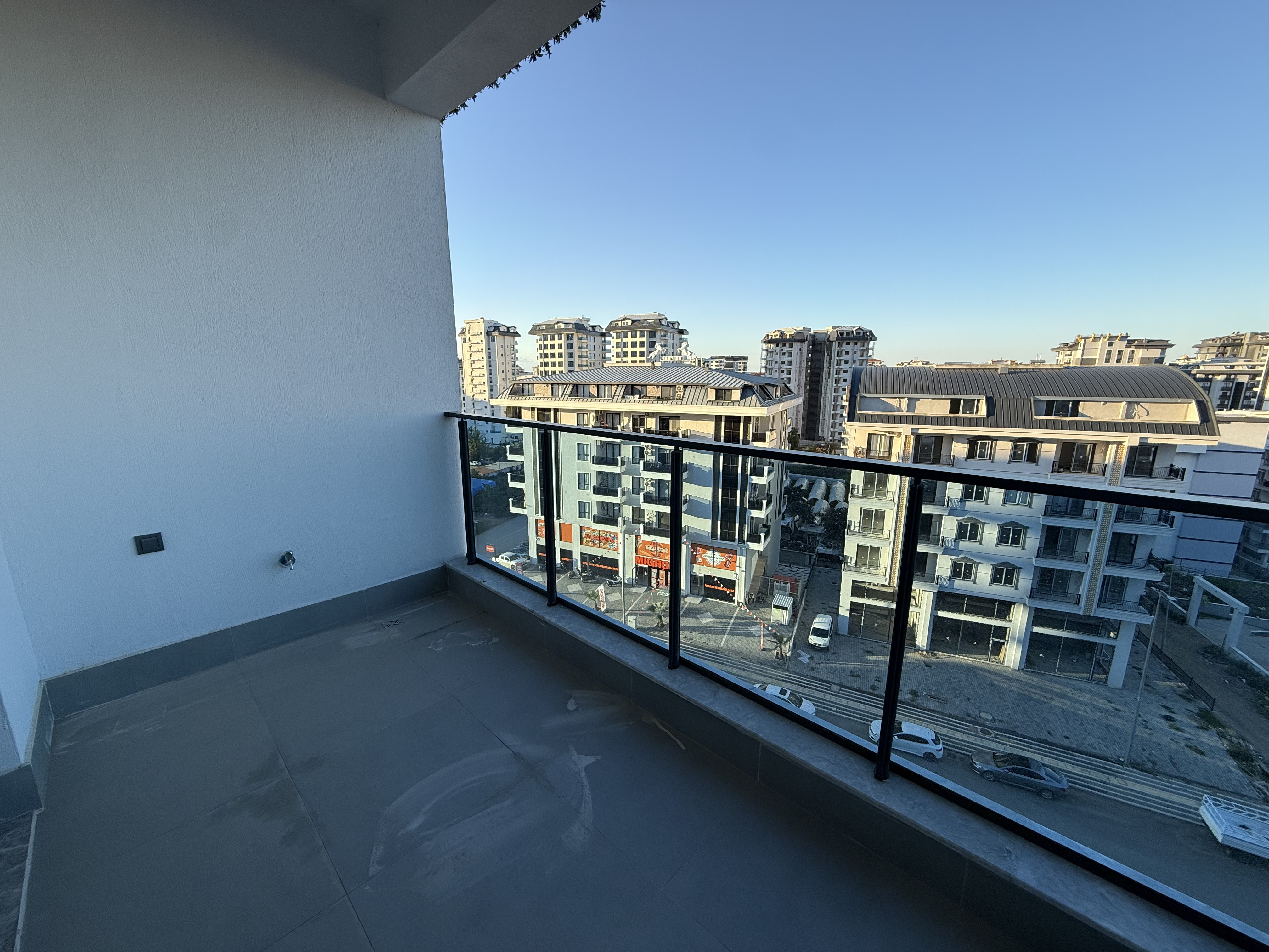 Open terrace with a glass railing and city views in an apartment in Mahmutlar