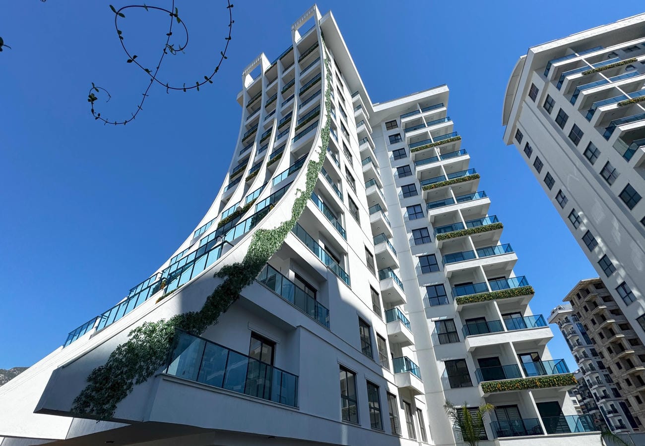 White residential building with glass balconies and panoramic glazing in Mahmutlar where homes are for sale