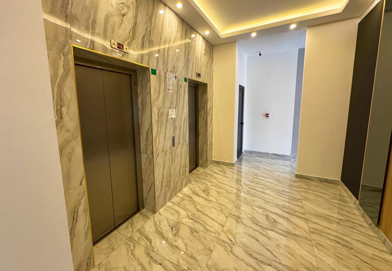Lobby with two enclosed lifts and marble finishes in a complex with apartments in Mahmutlar