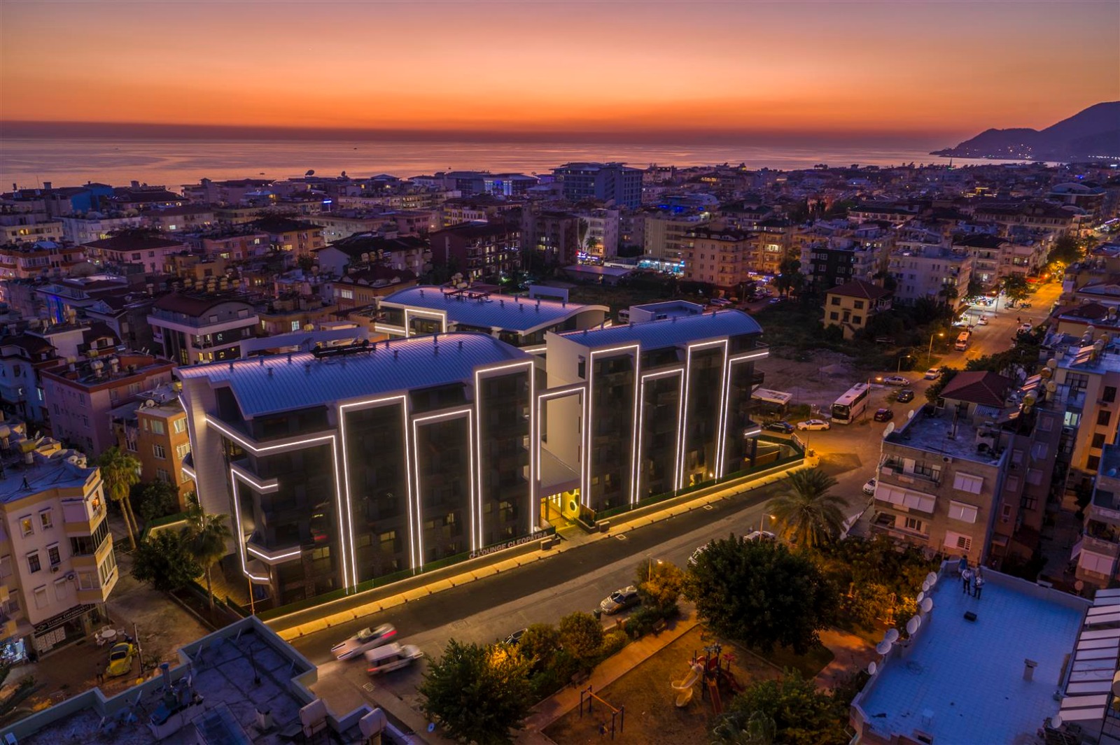 Akşam aydınlatmalı konut cephesi ve deniz ufku Alanya’da satılık dairelerin bulunduğu yerde