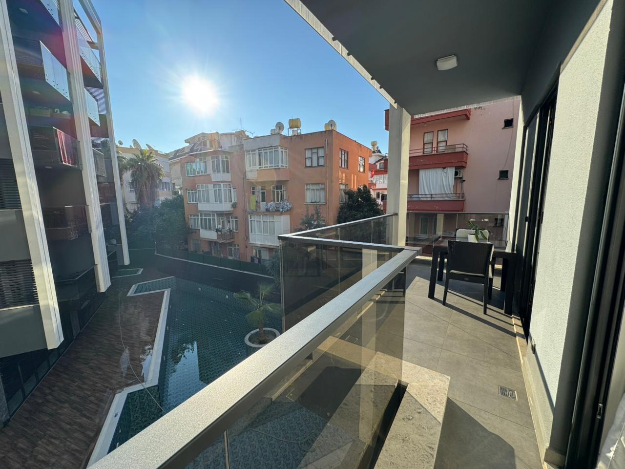 Cam korkuluklu balkon ve avlu havuzu manzarası Alanya’daki daireli konutta Türkiye’de