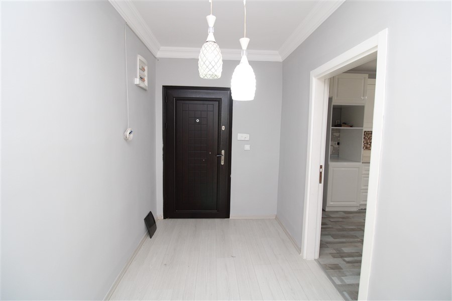 Siyah giriş kapılı antre açık renk laminat zeminiyle 2+1 dairenin içinde