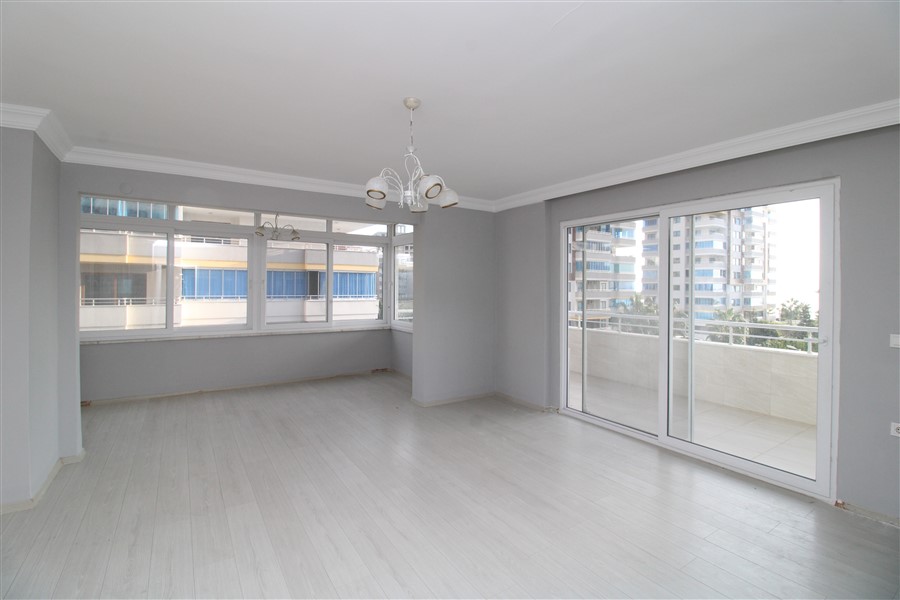 Panoramik camlı aydınlık salon sürgülü balkon kapısı ve komşu binalara bakış sunuyor