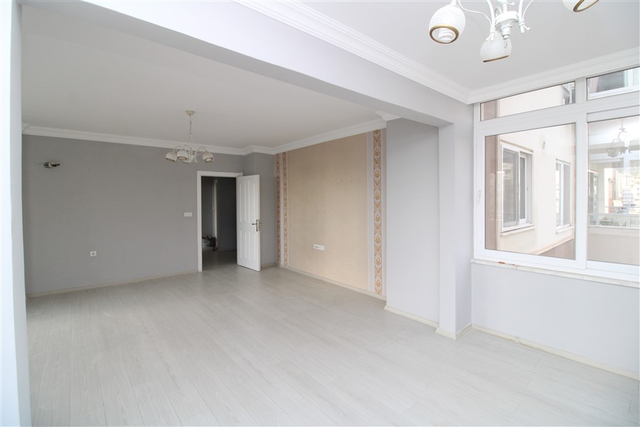 Gri duvarlı geniş salon ve panoramik camlar Türkiye'deki konutta ahşap zeminle birleşiyor