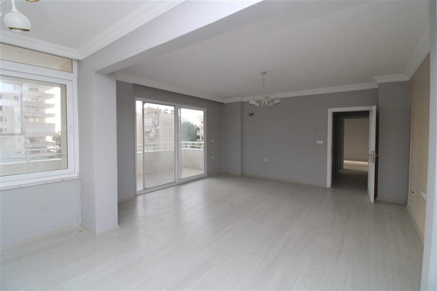 Açık planlı boş salon sürgülü balkon camı ve aydınlık ahşap zeminiyle Mahmutlar'da