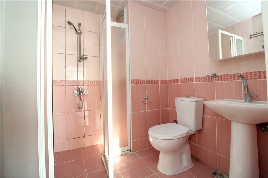 Pembe seramikli banyo duş seti ve kaideli beyaz lavaboyla 2+1 dairede
