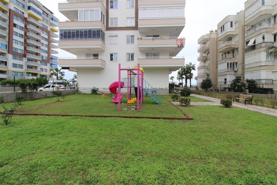 Pembe kaydıraklı çocuk oyun alanı daire sakinleri için yeşil çim ve banklarla çevrili