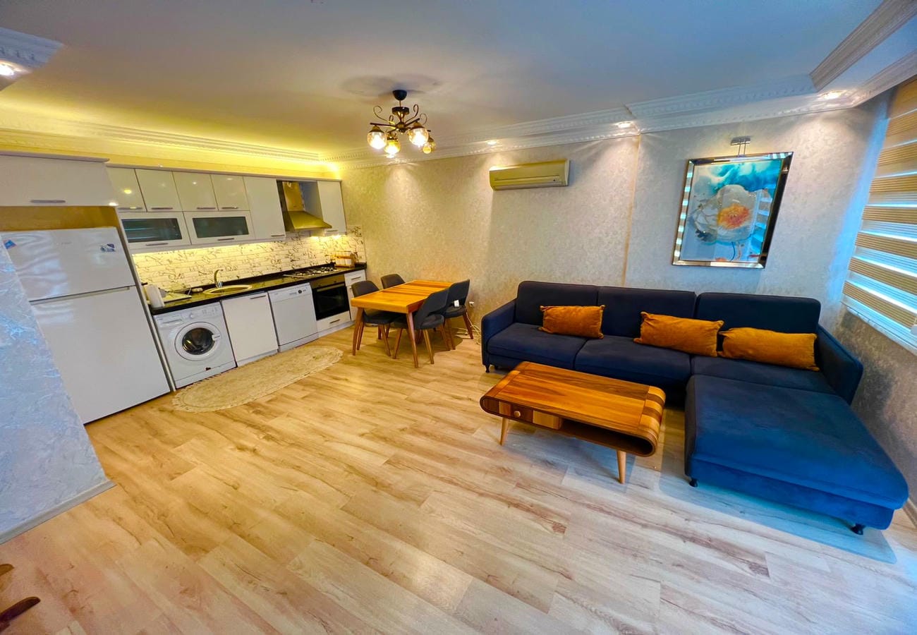 Turuncu yastıklı mavi kanepe ve beyaz mutfaklı mutfak-salon, Türkiye’de satışta 2+1 dairede