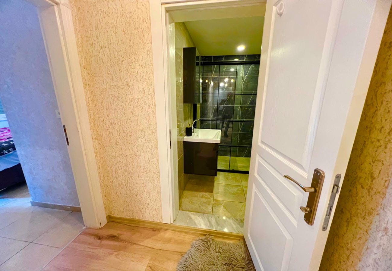 Beyaz lavabolu banyo, siyah duvar karoları ve ayna ile dairenin içinde