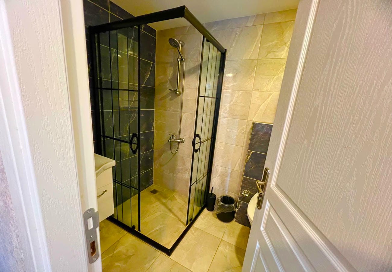 Siyah profilli duş kabinli banyo, beyaz lavabo ve klozetle Mahmutlar’daki dairede