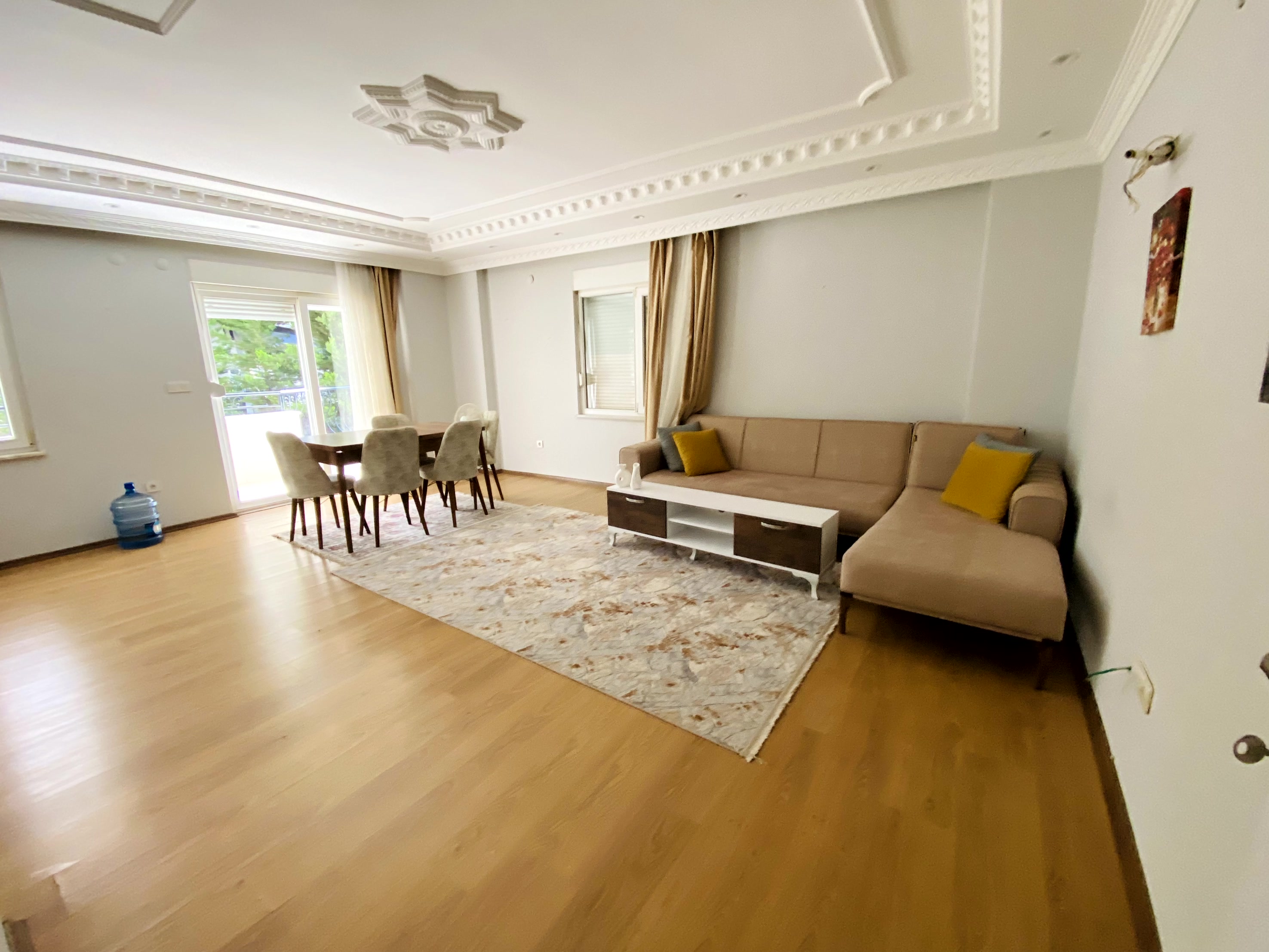 Yeşilliğe açılan balkon kapılı salon Mahmutlar’da satılık dairenin yemek alanıyla birlikte