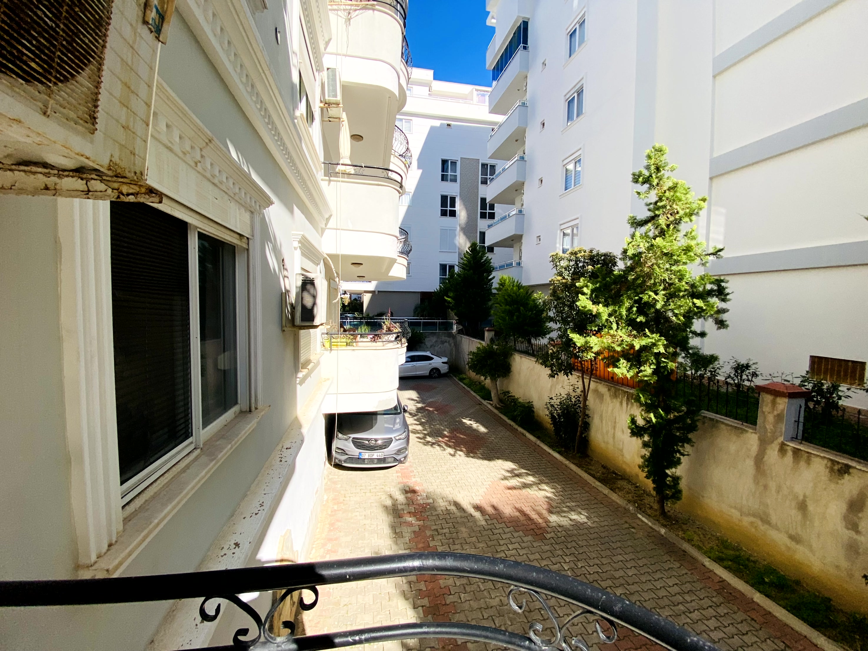 Ferforje balkon korkuluğu ve beyaz bina cephesi Türkiye’deki dairenin karşısında