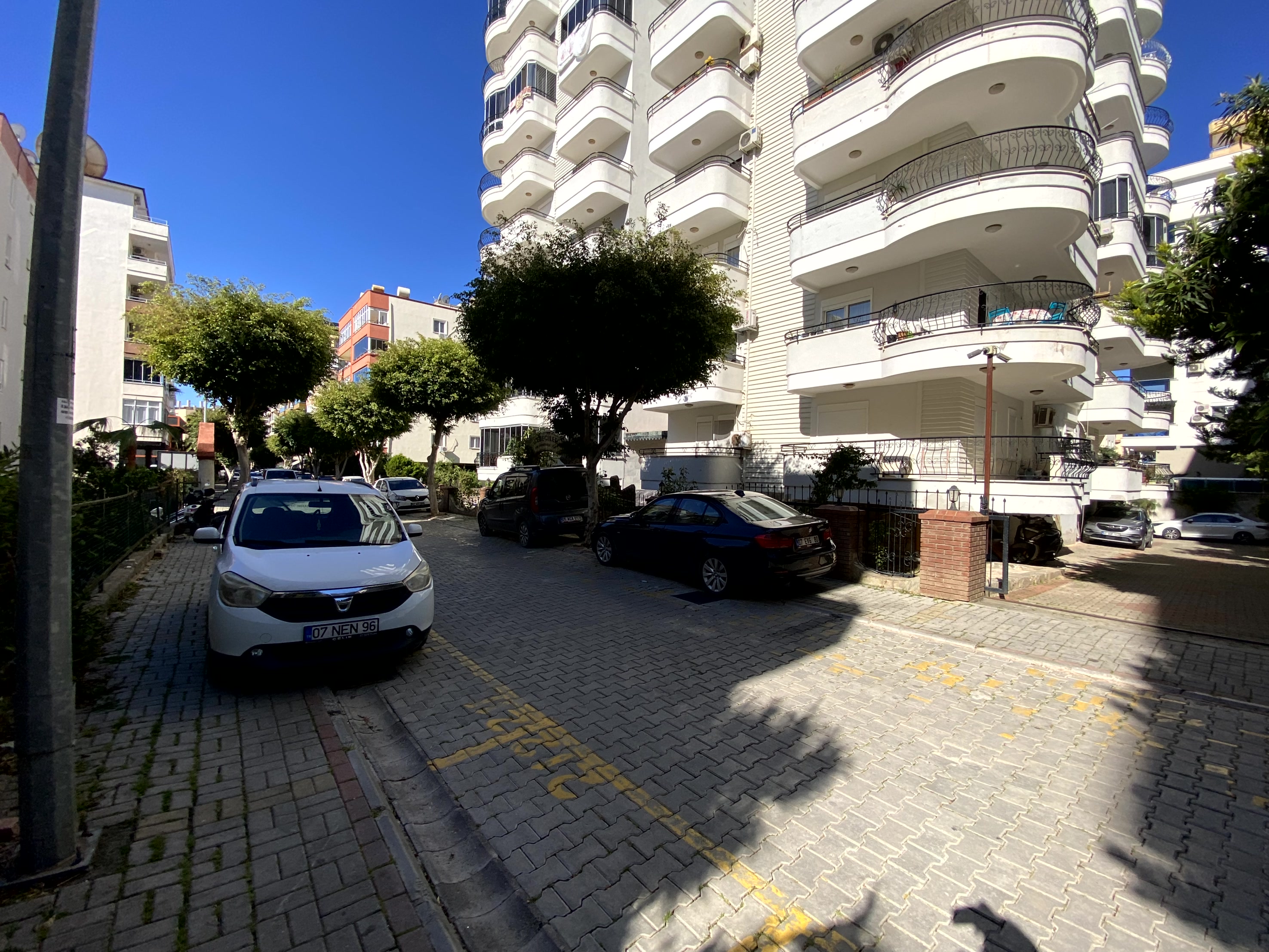 Beyaz cepheli binanın önündeki otopark Türkiye’de satılık konutların yanında