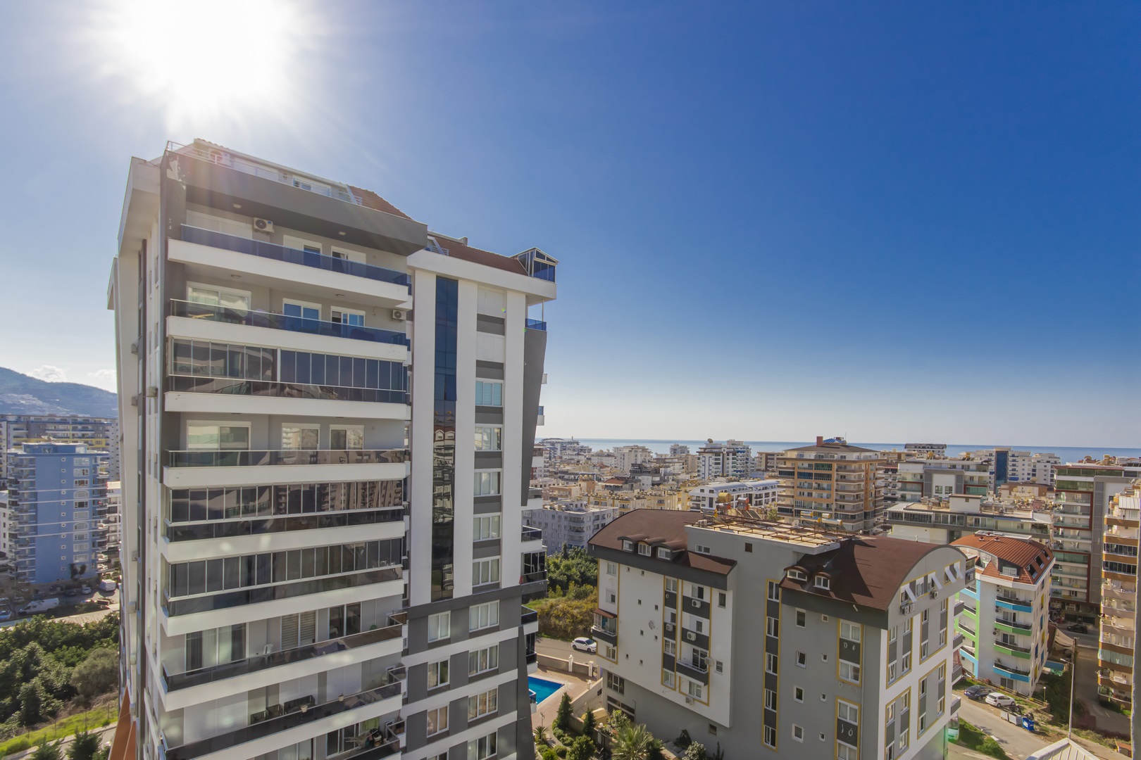 Mahmutlar’da satıştaki daireden şehir, avlu havuzu, deniz ve dağ sırtı panoraması izleniyor