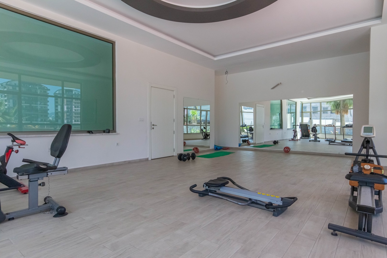 Daire sakinleri için spor salonunda koşu bandı, kürek ve sabit bisiklet, aynalı duvarın önünde