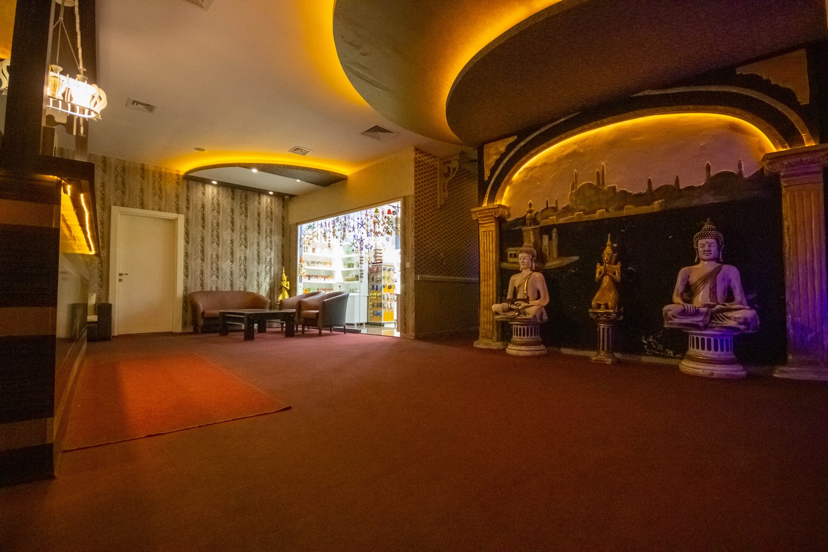 Konut sakinleri için spa alanında kıvrımlı ışıklı tavan, koltuklar ve heykelli dekoratif niş