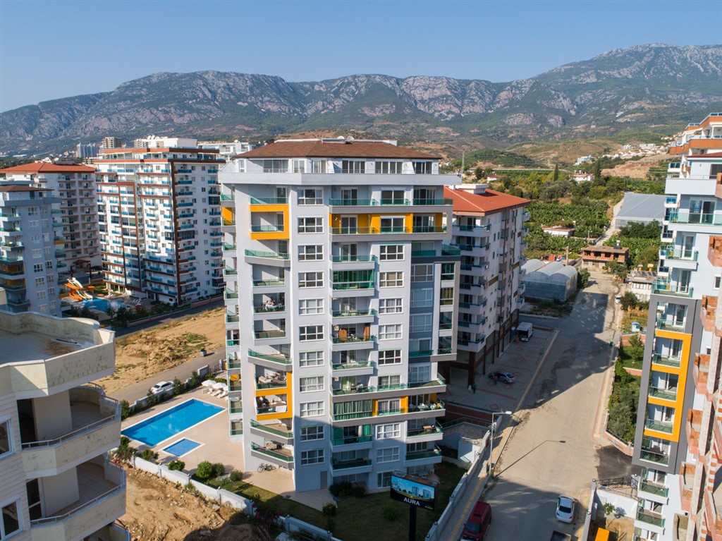 Açık havuzlu konut kompleksi ve dağ sırtı manzarası: Alanya Mahmutlar’da satılık 1+1 daire, Türkiye — New Level Group