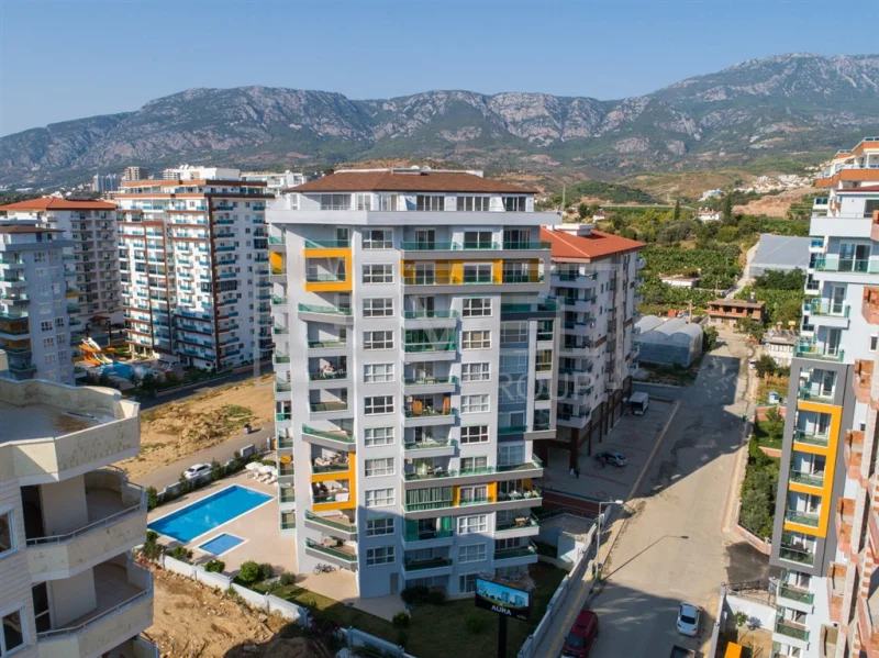 Açık havuzlu konut kompleksi ve dağ sırtı manzarası: Alanya Mahmutlar’da satılık 1+1 daire, Türkiye — New Level Group