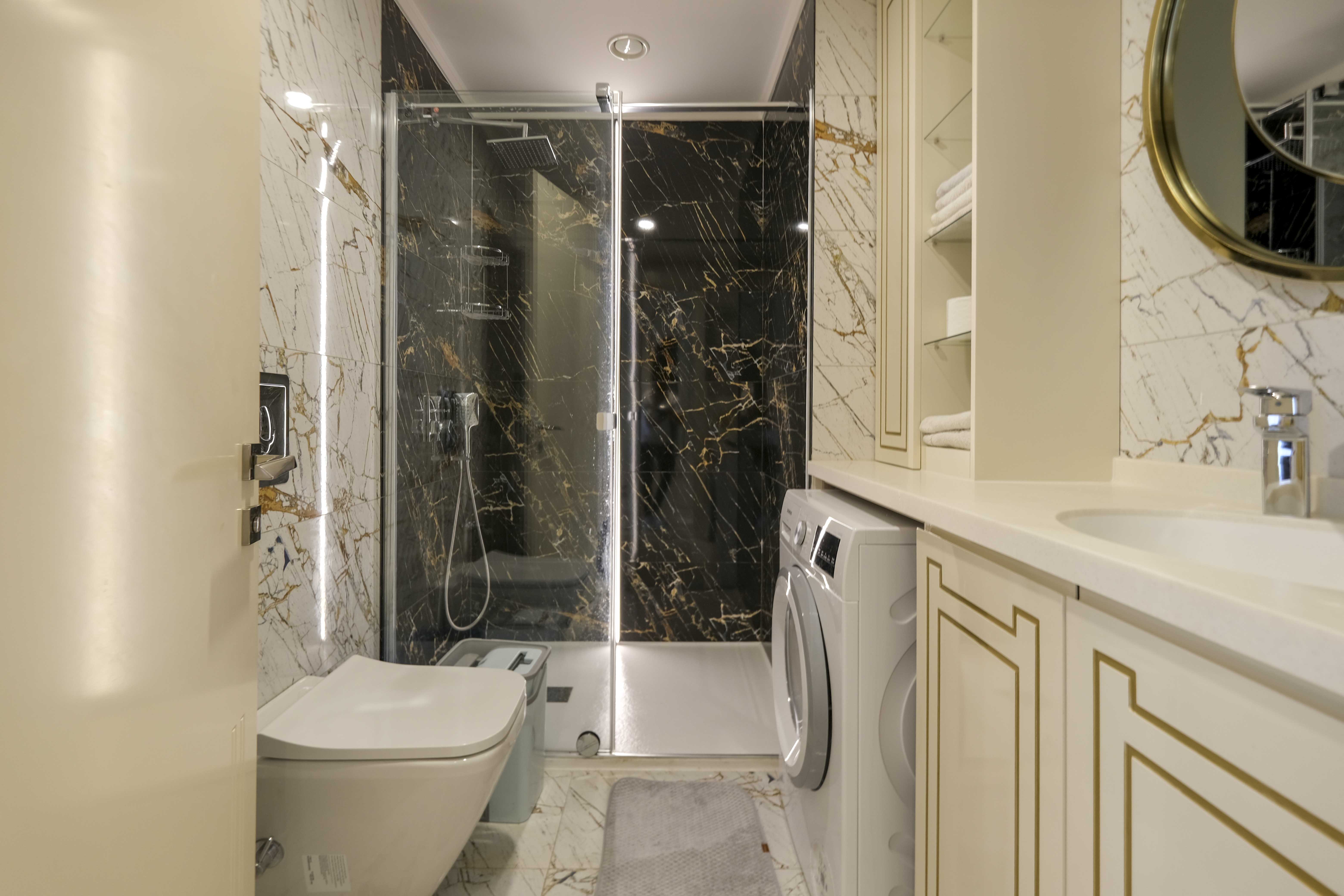 Ванная комната с душевой кабиной, мраморной плиткой и стиральной машиной в Махмутларе
