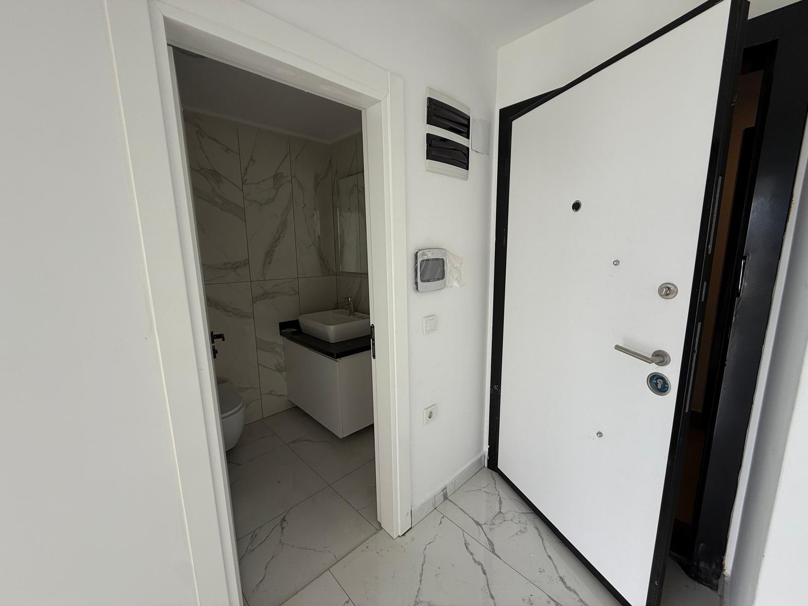 Entry hall with white marble flooring and a view into the bathroom with a vanity