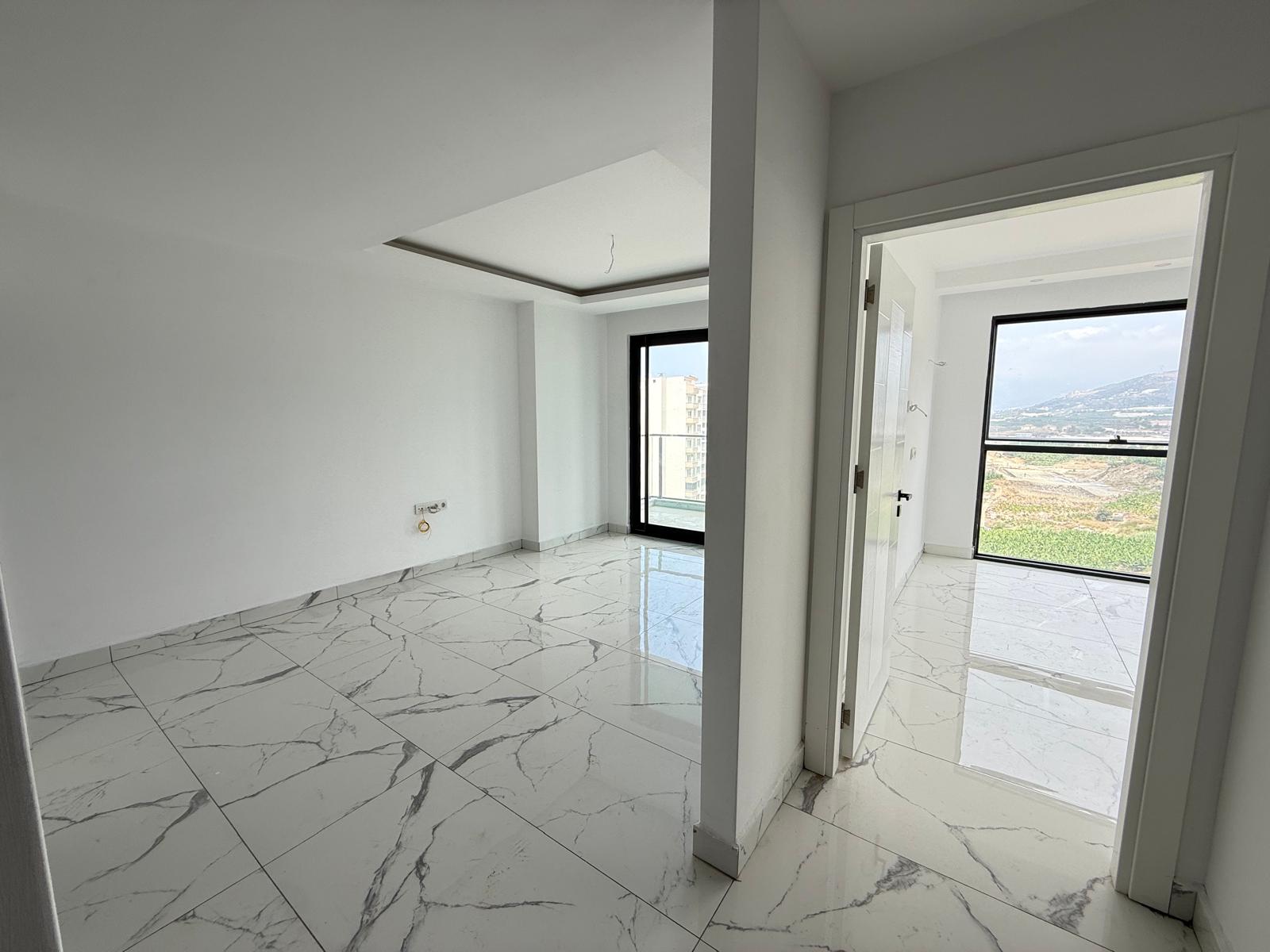 Living room with white marble flooring and a mountain view in a flat in Mahmutlar