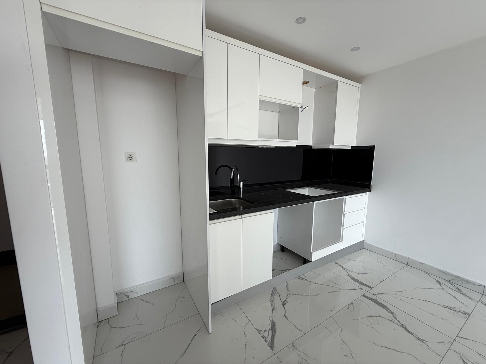 Kitchen with white cabinetry, black worktop and integrated sink in an apartment