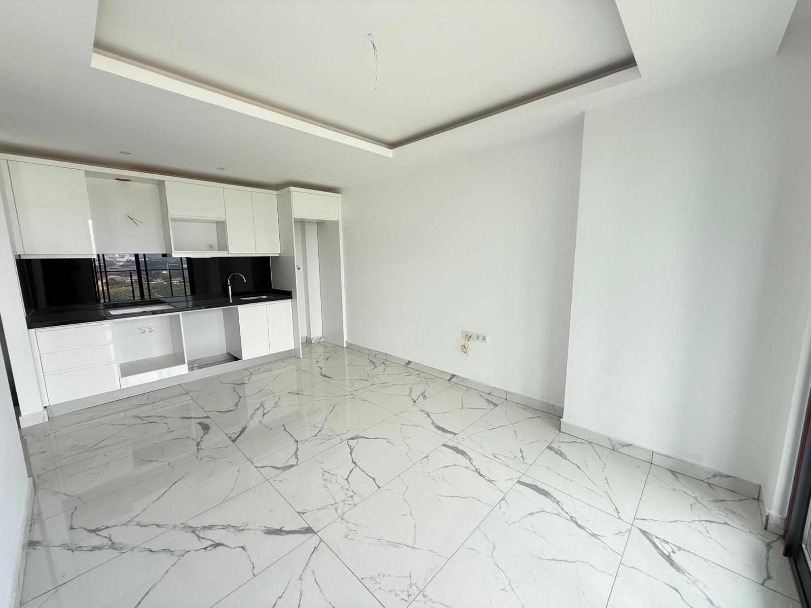 Kitchen-living room with white cabinetry, black worktop and panoramic glazing in a residence