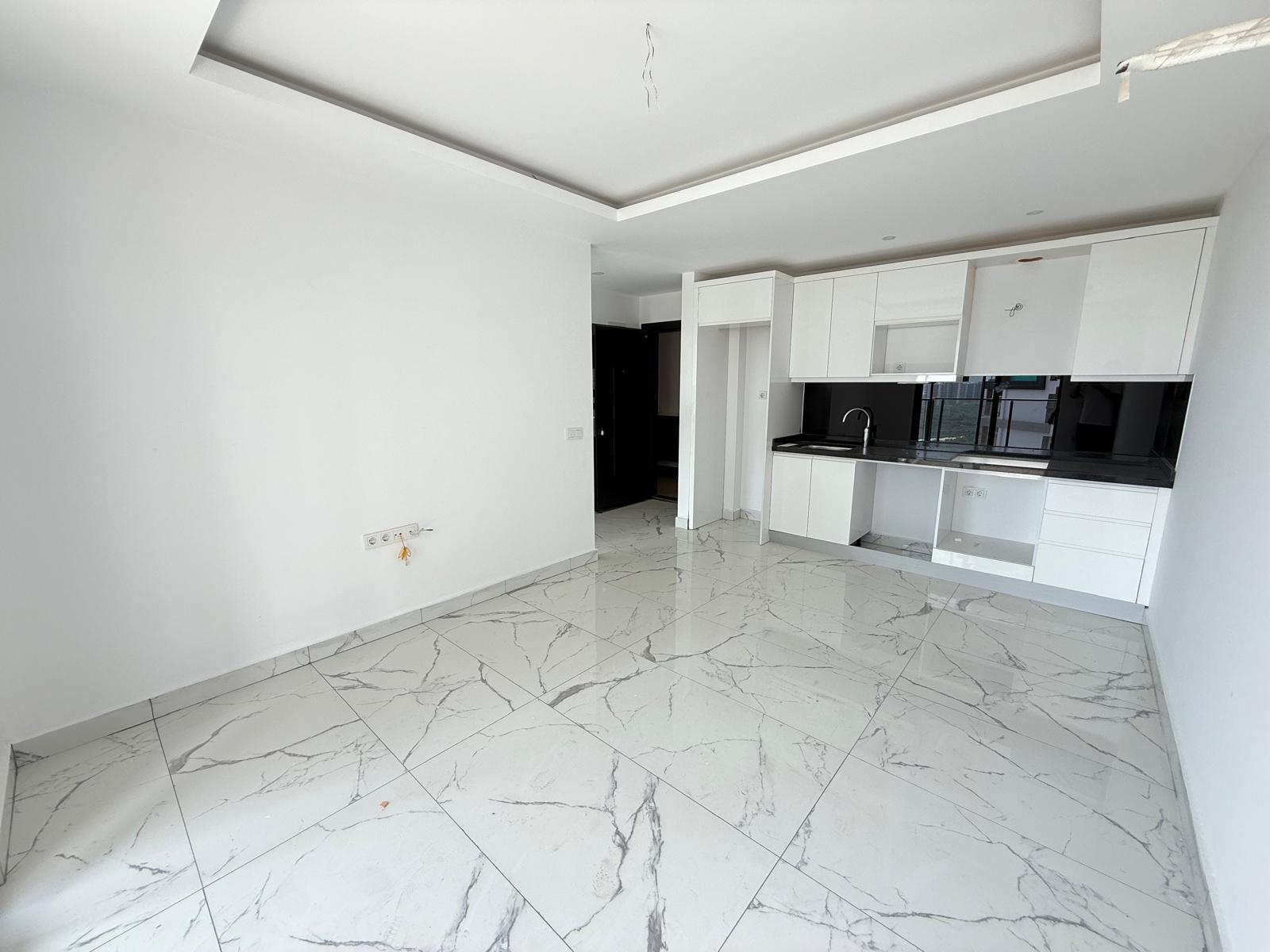 Kitchen-living room with linear white cabinetry and a separate sitting area in a flat in Mahmutlar