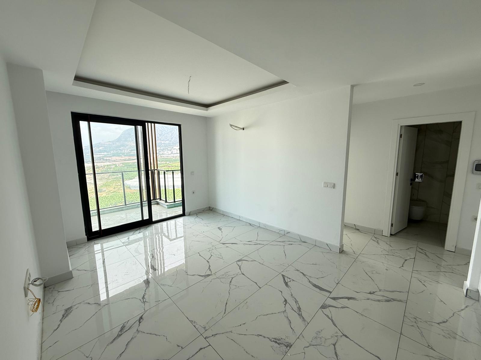 Living room with panoramic balcony door and marble-patterned floor in a home for sale