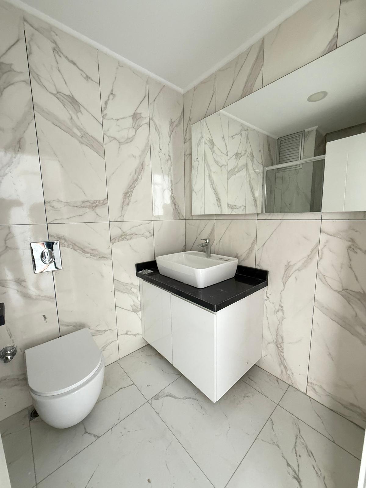 Bathroom with a bowl sink, black worktop and marble walls and floor in an apartment