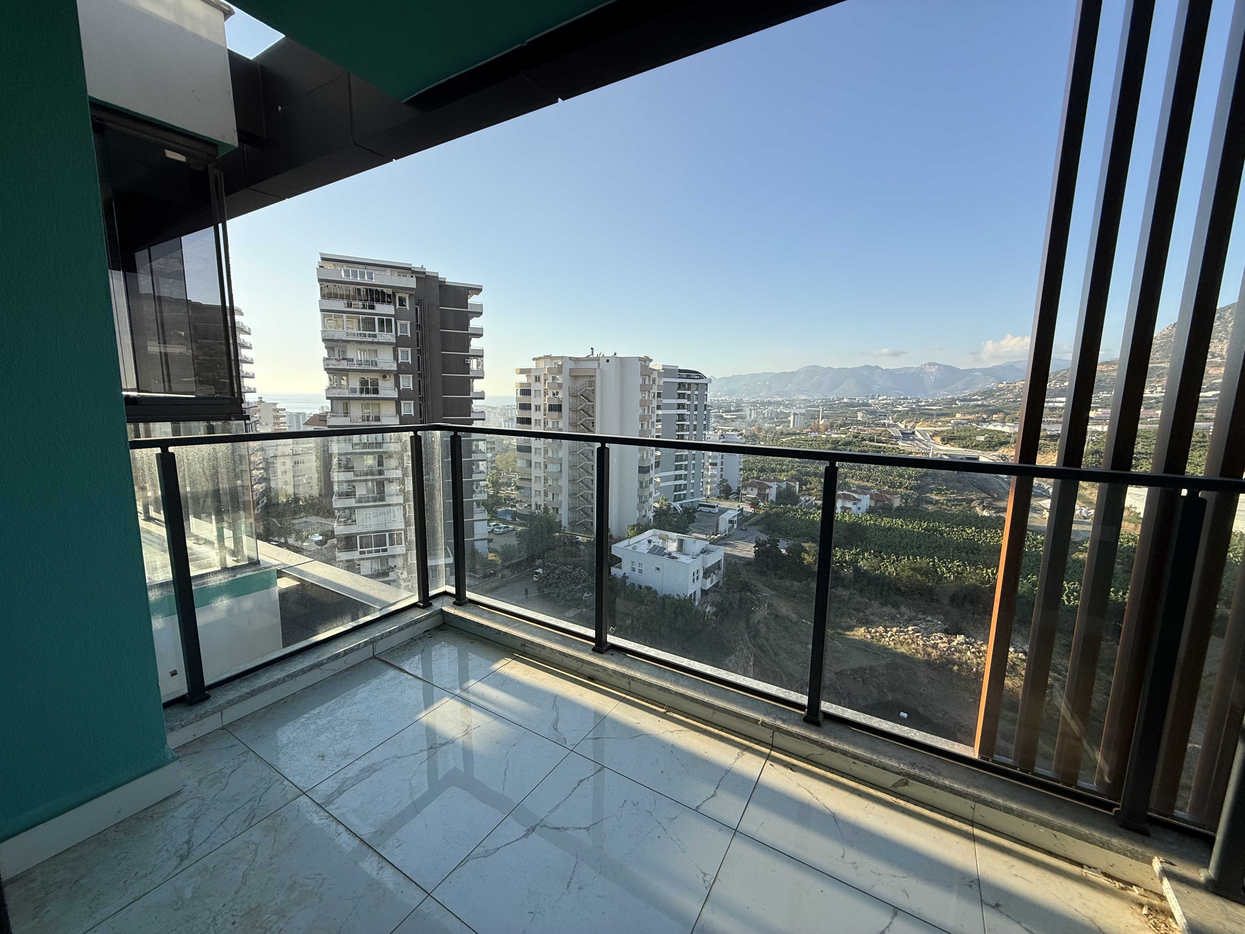 Corner balcony with panoramic glazing and mountain scenery beside residential buildings in Turkey