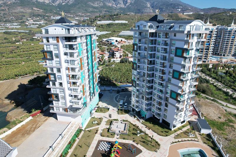 Aerial view of two residential buildings, pool and play area in a complex with flats for sale in Turkey