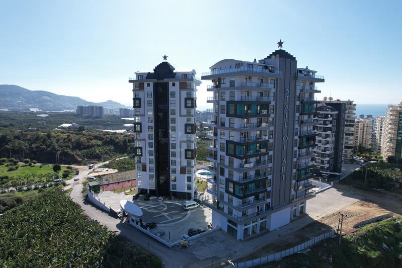Entrance area and sports court with sea in the distance at a residence with apartments in Mahmutlar, Turkey