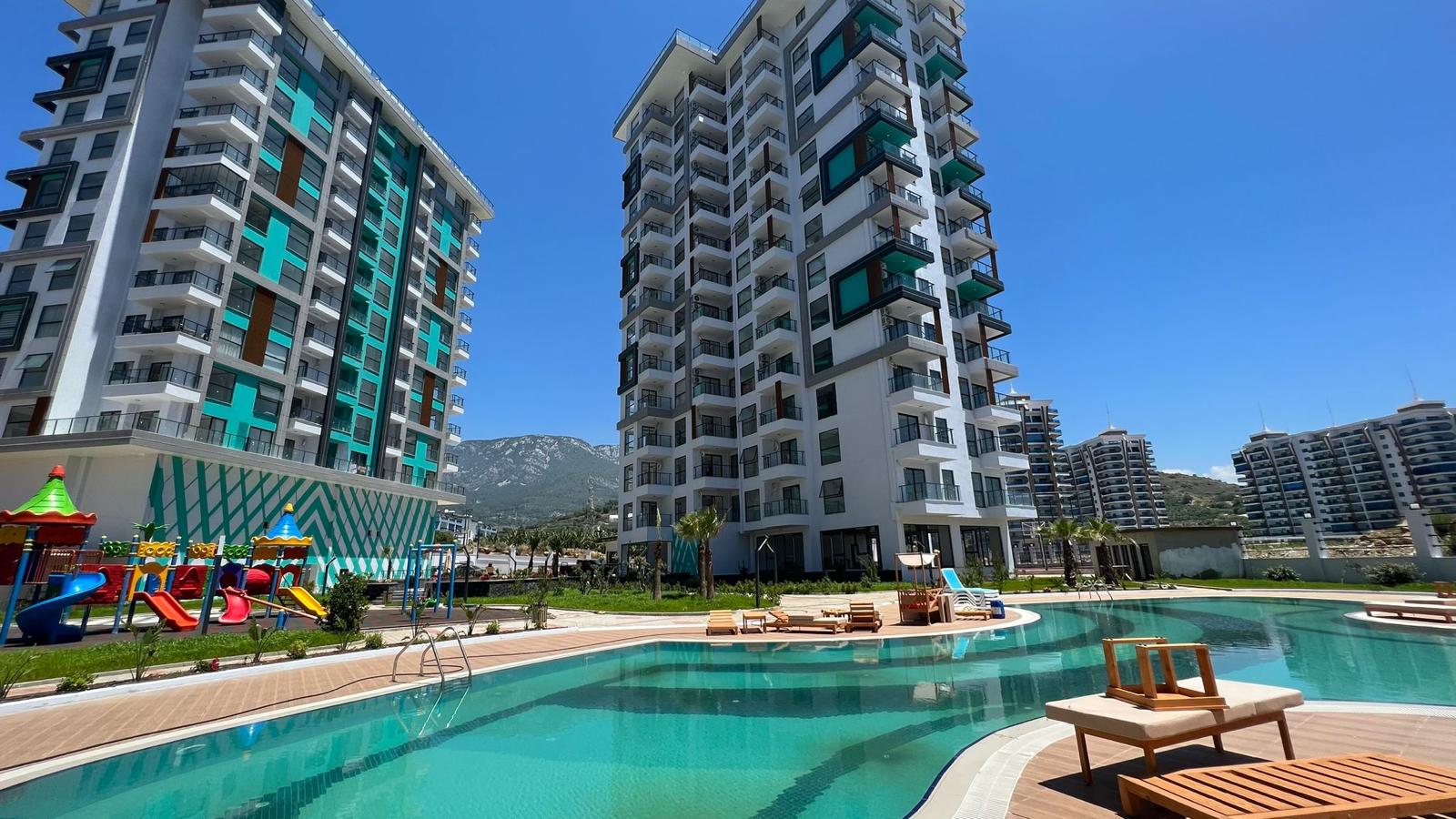 Curved pool with loungers: a 1+1 apartment for sale in Mahmutlar, Alanya, Turkey — New Level Group
