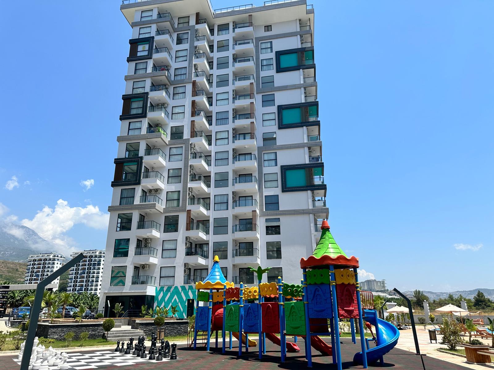 Children’s playground with slides and giant chess pieces on a residence with flats for sale in Mahmutlar