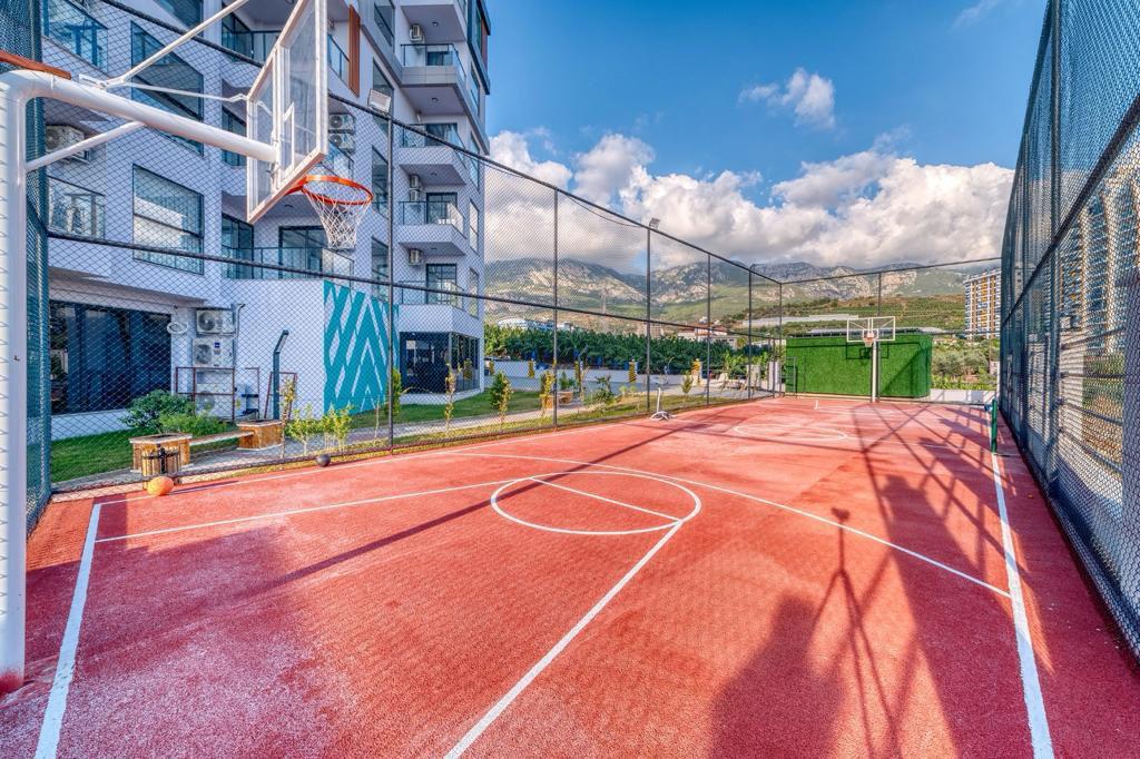 Outdoor basketball court with hoops and mesh fencing in a complex with apartments