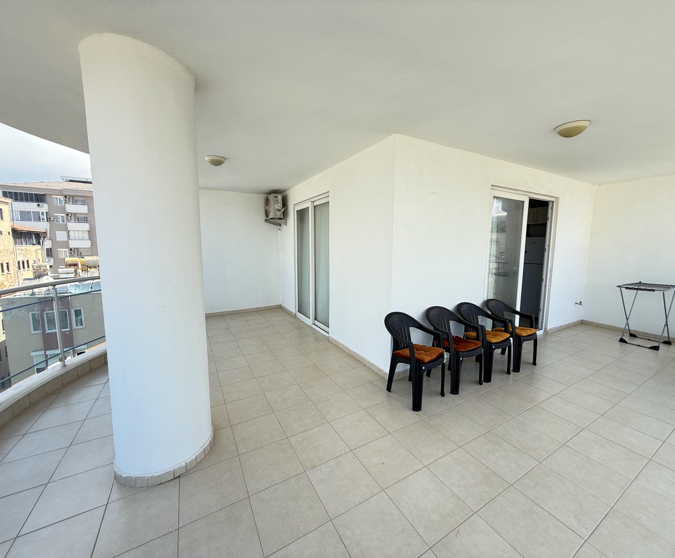 Geniş kapalı teras Mahmutlar’daki 2+1 dairede panoramik camlar ve büyük beyaz kolon içeriyor