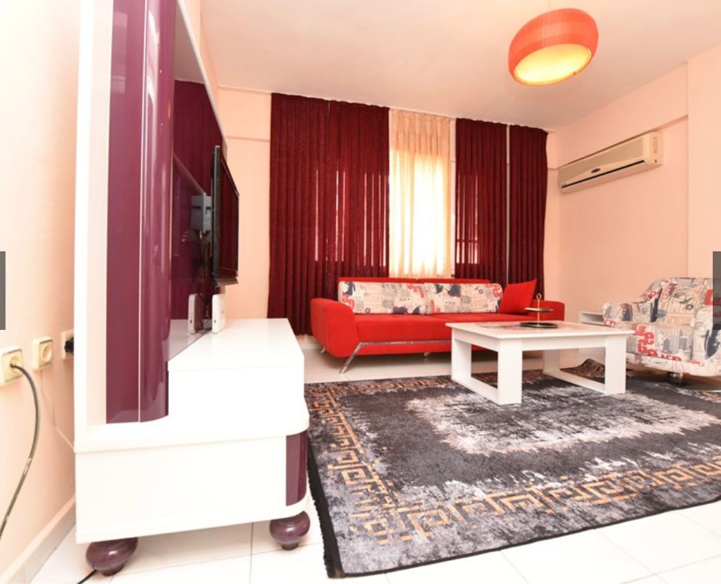 Televizyonlu salon, Mahmutlar'da satılık dairenin desenli koltuklar ve bordo perdelerle döşenmiş