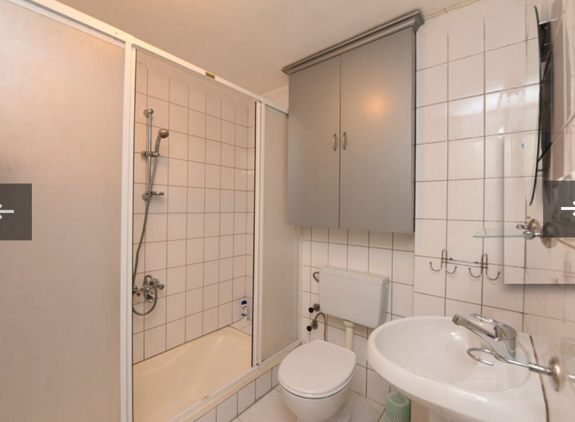 Cam kapılı duş kabinli banyo, Mahmutlar'daki dairede krom bataryalı lavabo ve duvar askıları bulunuyor