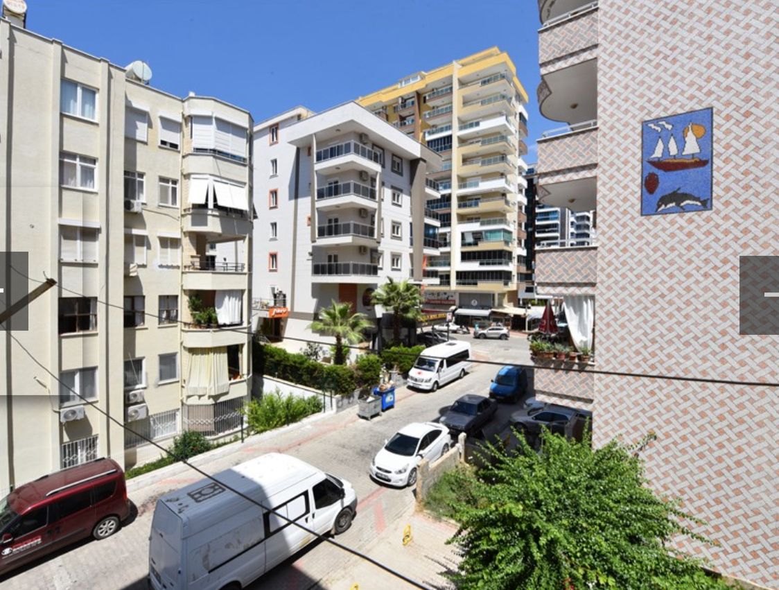 Palmiyeli şehir sokağı, Türkiye'de satılık konutların bulunduğu caddede mağazalar ve çok katlı binalar görülüyor