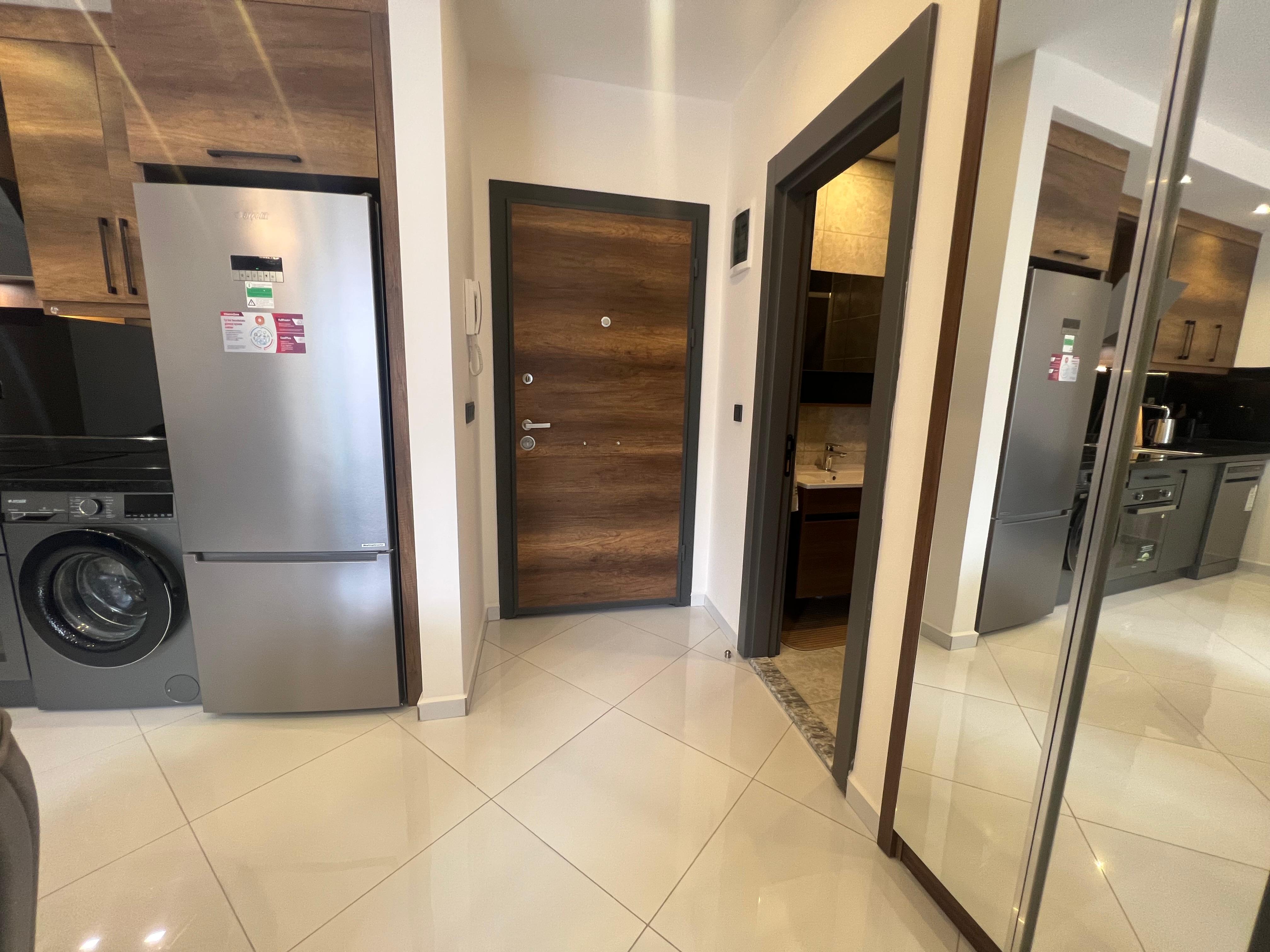 Entrance hall with a silver refrigerator and mirrored wardrobe in a flat in Mahmutlar