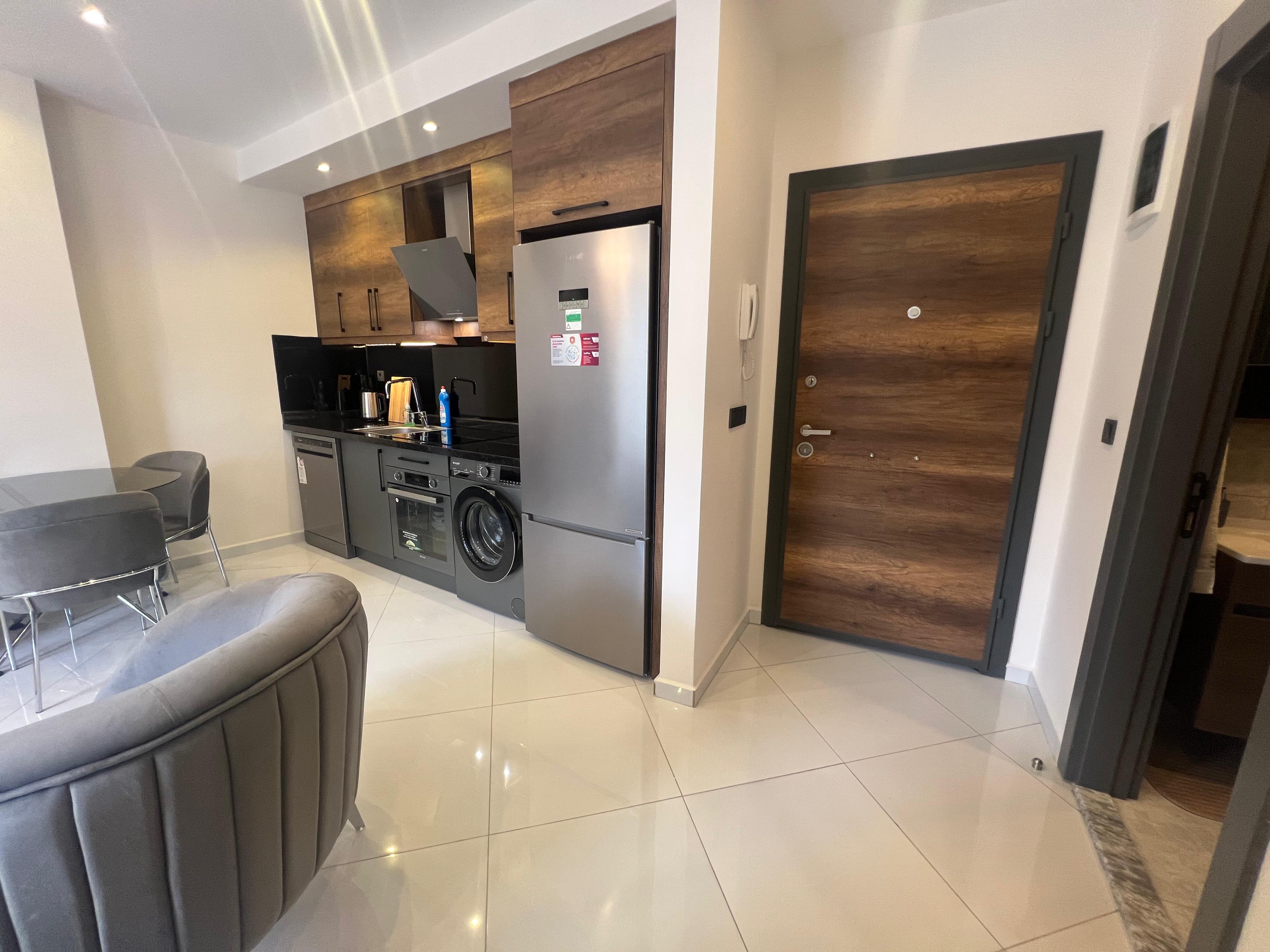 Kitchen-living room with a gray sofa and wood-effect cabinets in an apartment