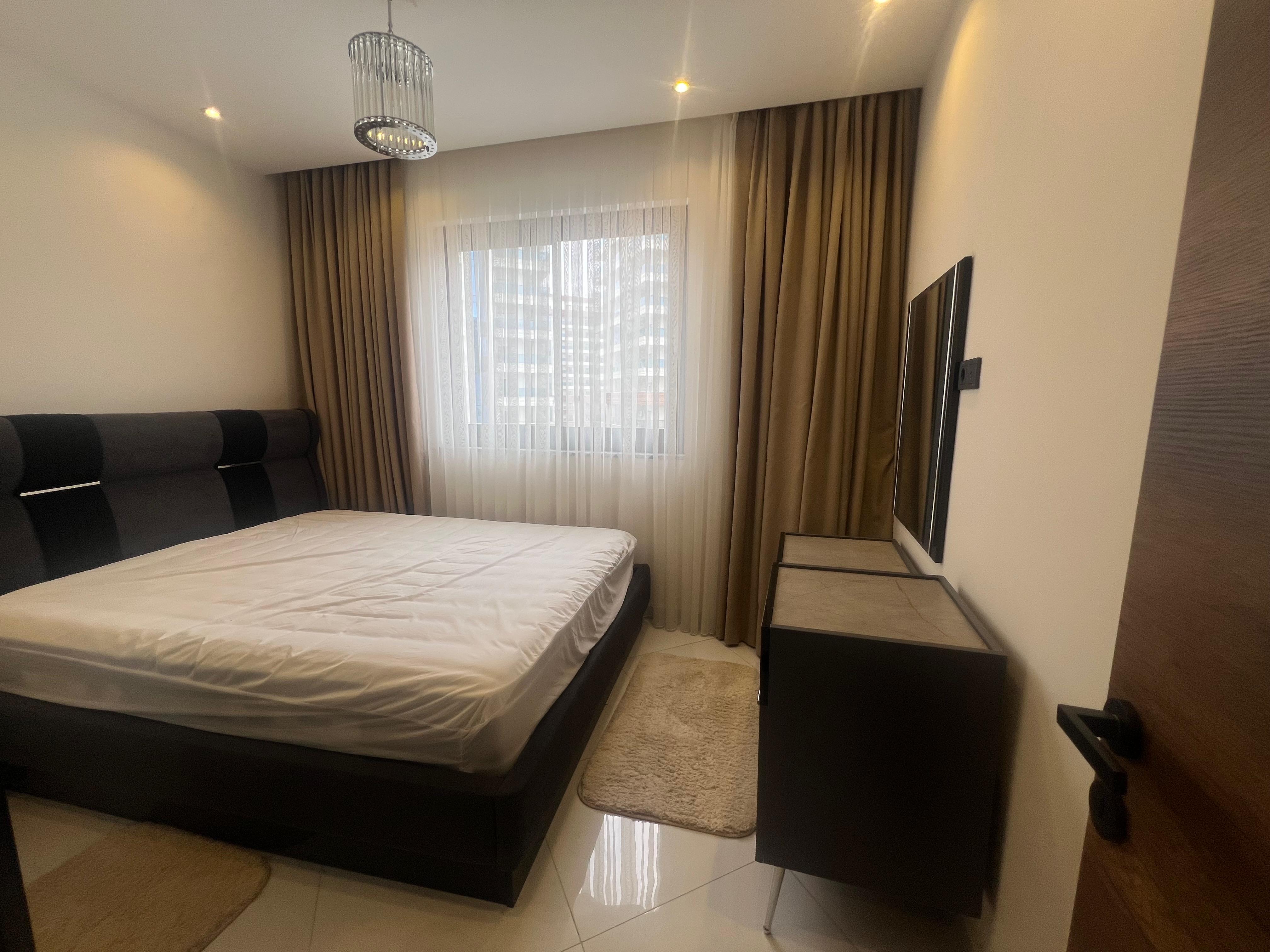 Bedroom with a double bed and panoramic window in an apartment in Mahmutlar